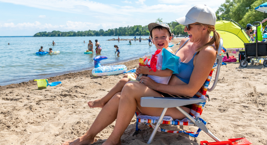 Person sitting in a chair on the beach holding a child