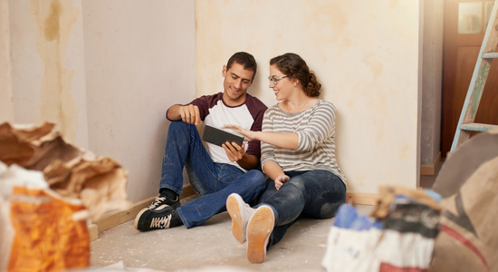 Two people seated on the ground looking at a tablet